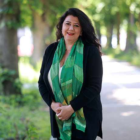 A photograph of Professor Monica D'Onofrio smiling in front of a background filled with trees and sunlight