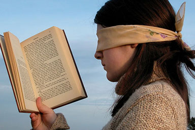 A blindfolded woman looking at a book