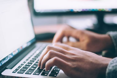 Hands typing on a laptop