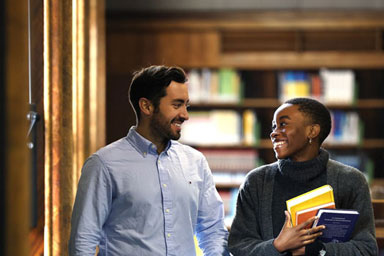 Two students in a library, smiling