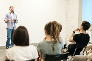 A researcher standing in front of seated young people