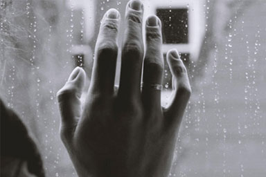 A hand against a rainy window