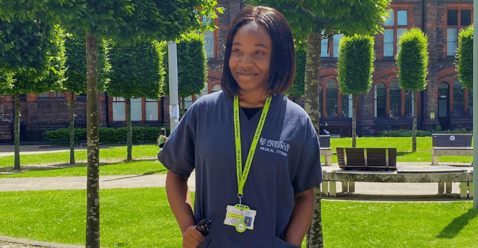 student doctor in scrubs in a green square on campus