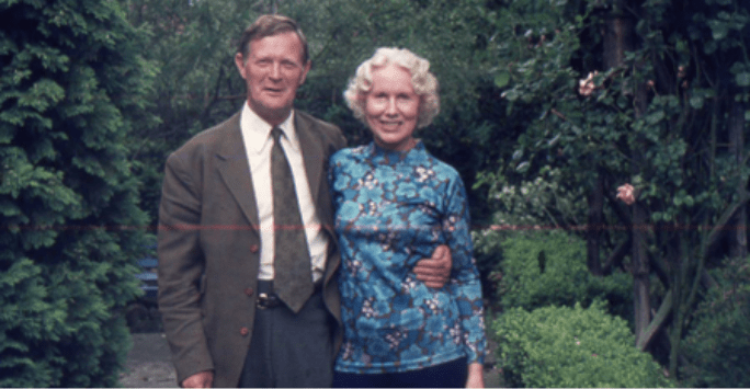 a couple pose in the garden with arms around each other