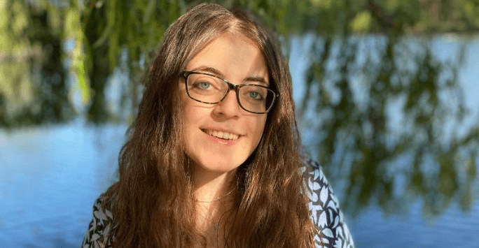 woman outdoors with green trees and water in the background