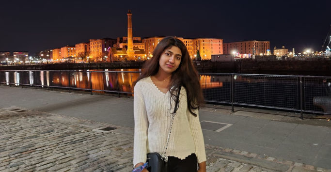 student smiling with the Liverpool waterfront in the background