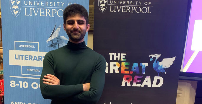 student stands cross armed in front of posters with The Great Read written on them