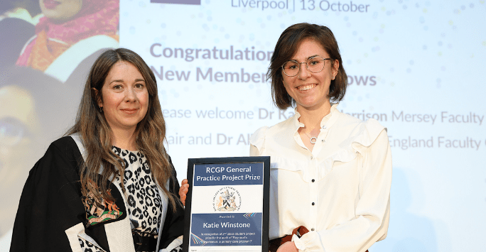 woman wearing robe presents certificate to woman in formal wear