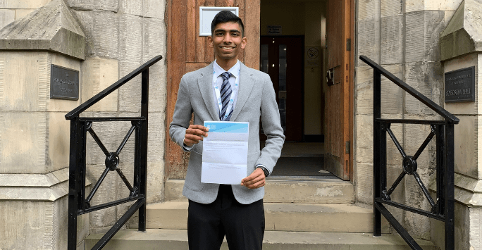 student poses on steps with certificate