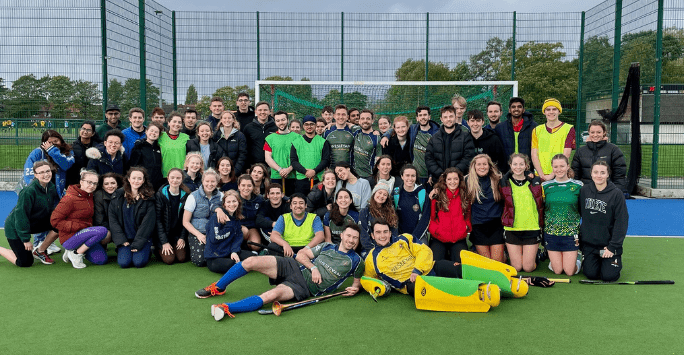 large group of hockey players pose for camera on hockey field