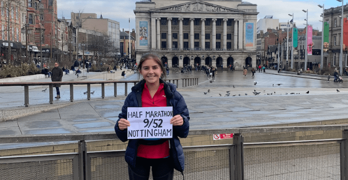 marathon runner holding sign in front of monument