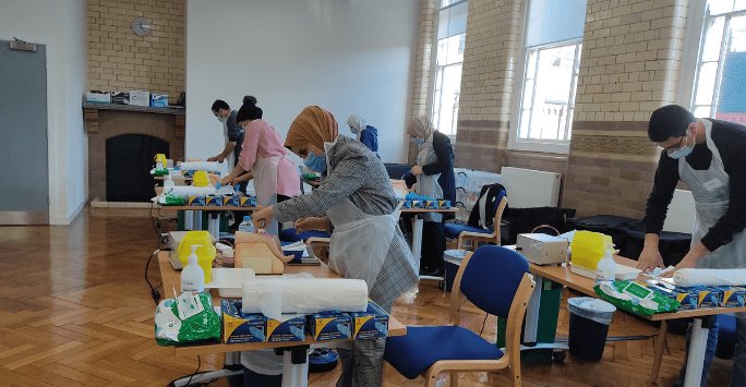 People wearing PPE practice clinical skills in a classroom setting