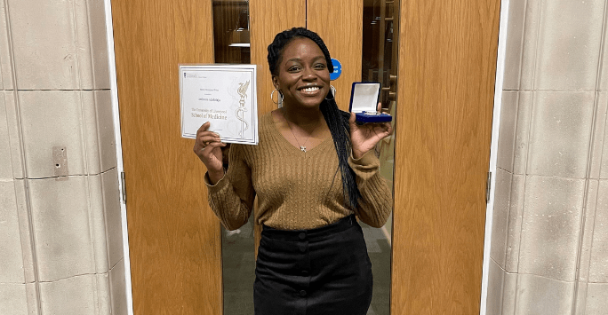 student poses with certificate and medal