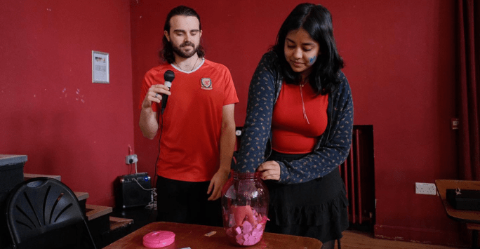 a man on the microphone and a woman drawing a raffle