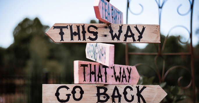 sign giving directions in the style of alice in wonderland