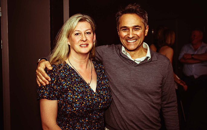 a man and woman with arms around each other smile to the camera