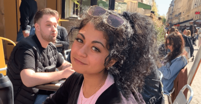 woman sits at an outdoor table