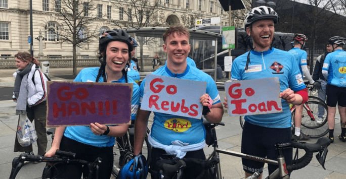 Students smile on bikes holding signs of encouragement