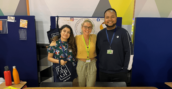 three students pose at a stall