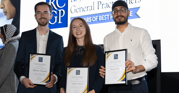 three students pose with certificates in front of big screen