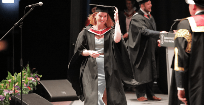 graduate in cap and gown at graduation ceremony