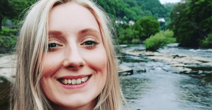 woman surrounded by nature with river in background