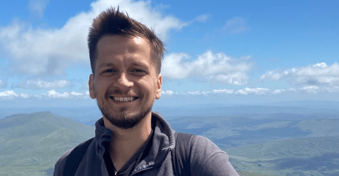 man in hiking gear on a mountain with blue sky