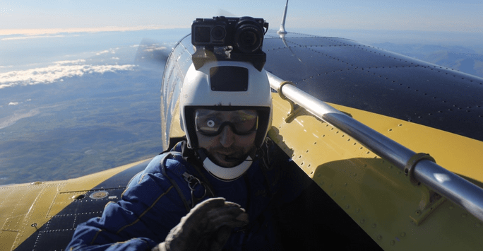 Man with camera on helmet on outside step of aircraft