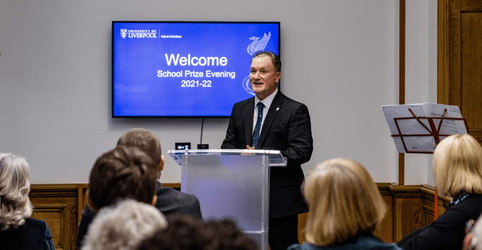 a men presents at a lecturn with welcome to prize evening slide in the background