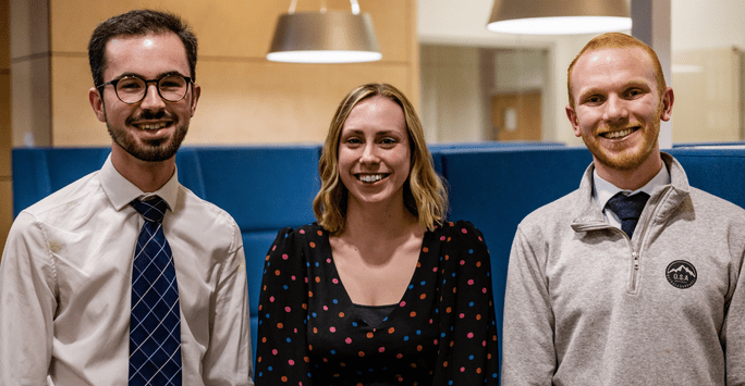 a woman and two men smile for the camera