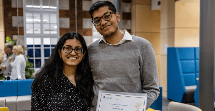 a man holding a certificate poses with a woman, both smiling