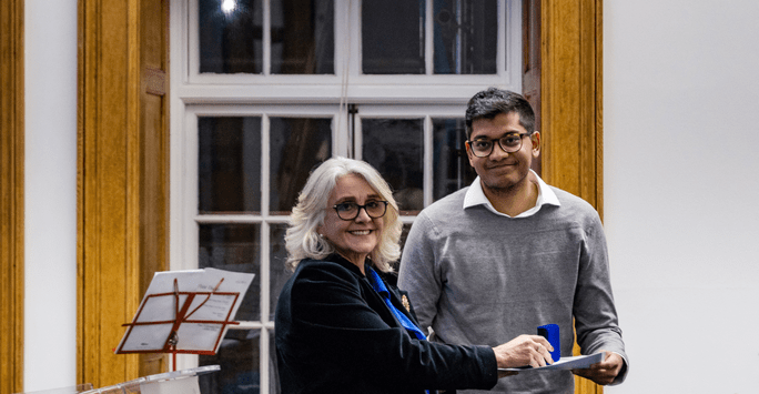 a woman presents a man with a certificate and medal