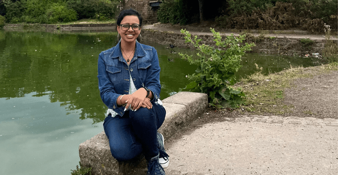 woman sits on the side of a lake