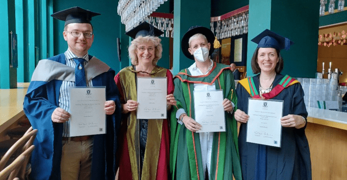 group of people in graduation gowns holding certificates