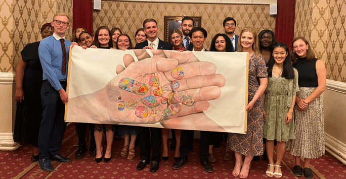 conference participations holding a large sign with an image of the palms of hands