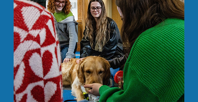 Students smiling with Ralphie the dog