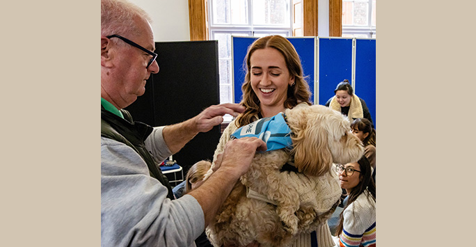 Student smiles holding Paddy the dog