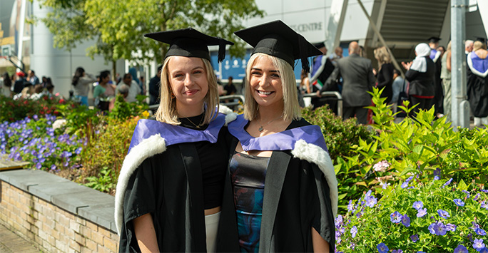 Two graduates smiling outside