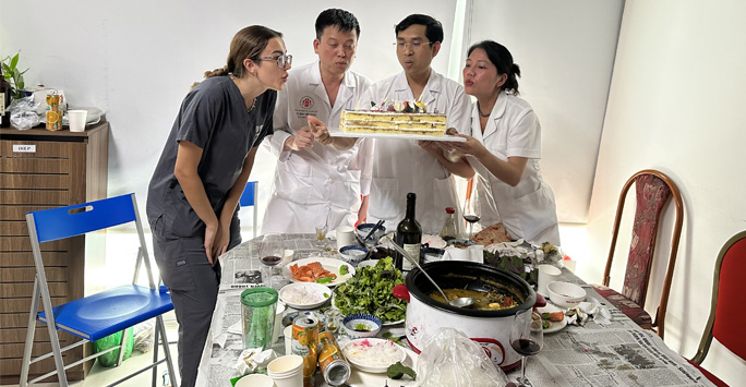 Student doctor Semay celebrates her birthday with three other doctors, all blowing out candles on a birthday cake.