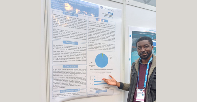 Student stands in front of his poster presentation board