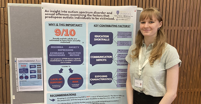 Student Esther stands in front of her poster presentation board