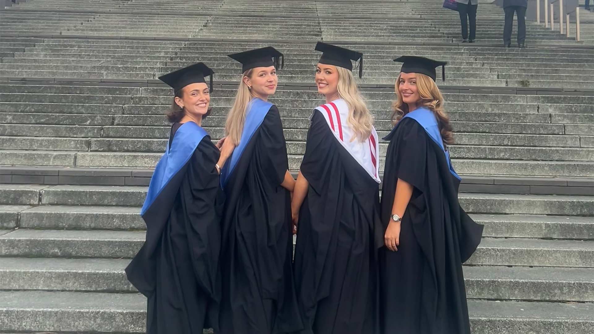 women in caps and gowns on cathedral steps