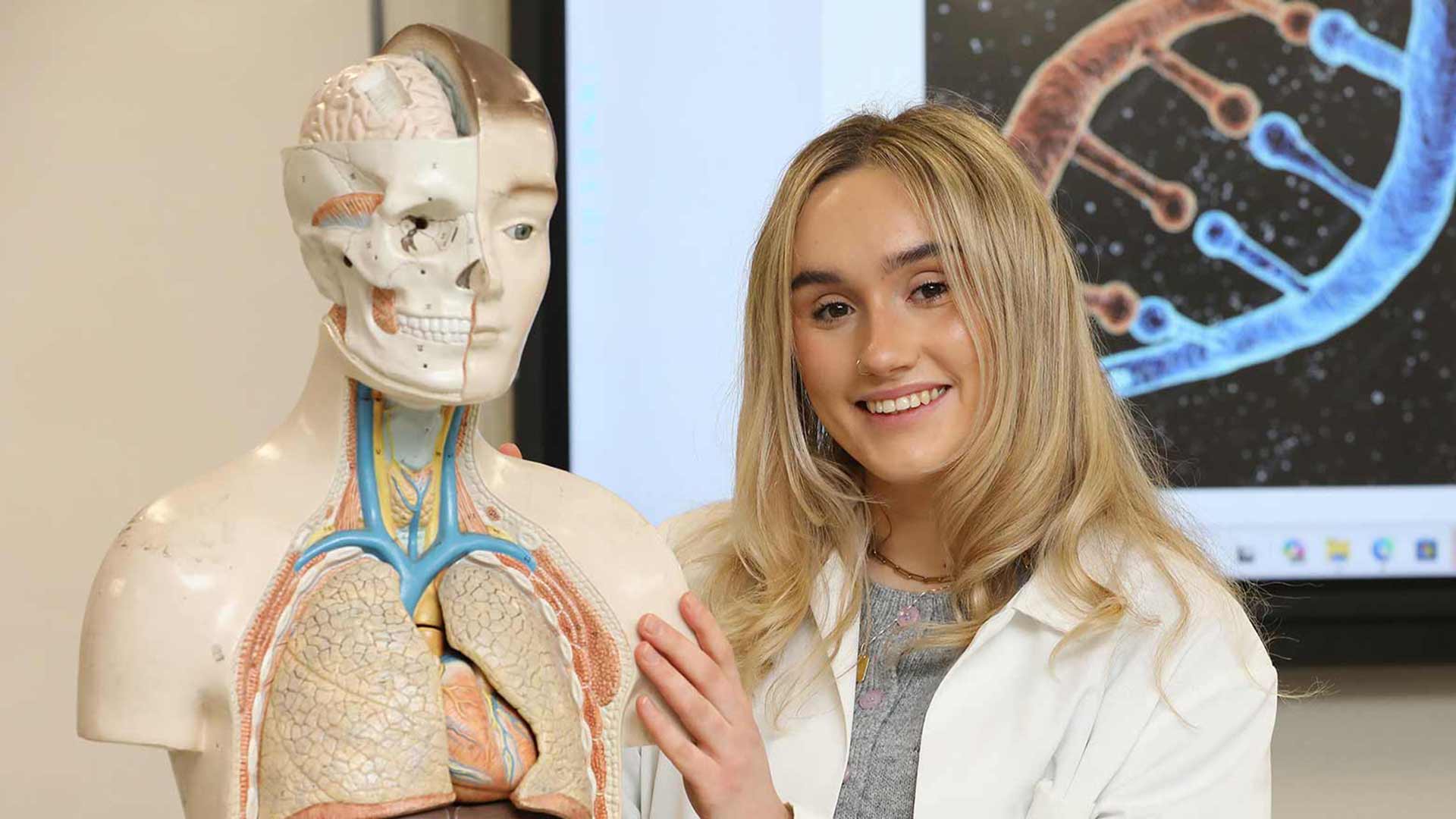 student in lab coat with anatomy equipment