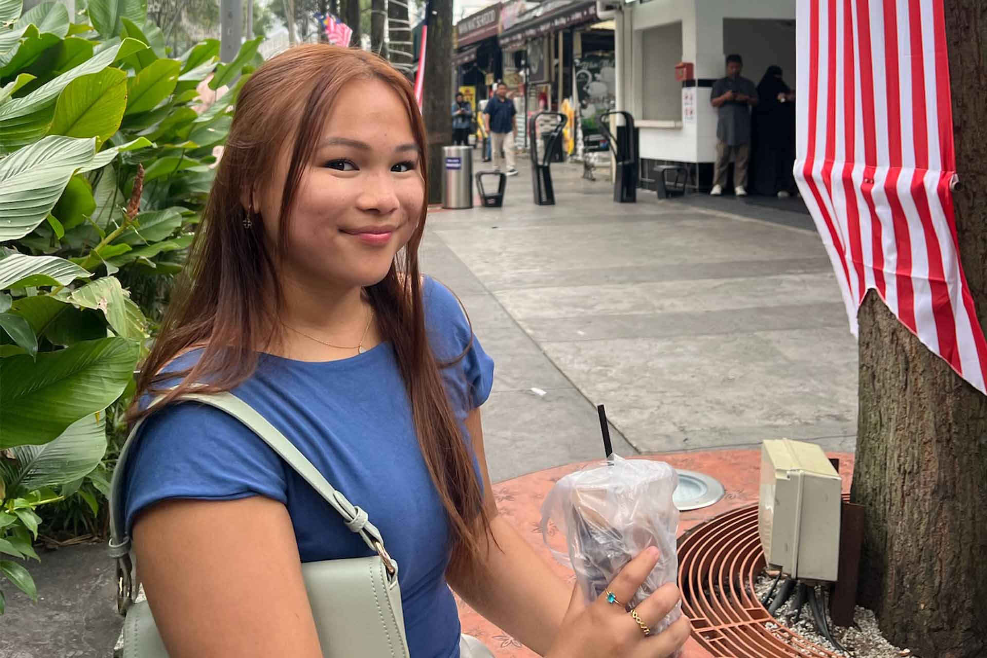 a woman on a city street with a plastic cup with straw