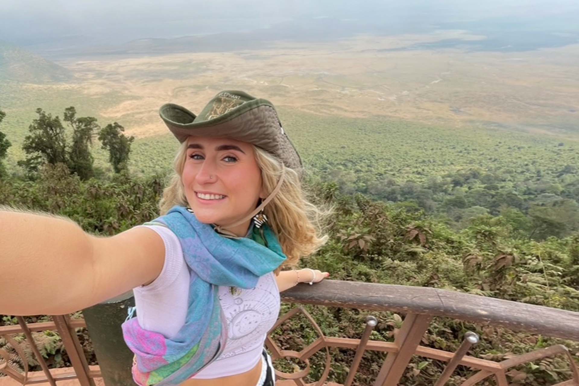 woman in hat takes selfie in front of a large valley