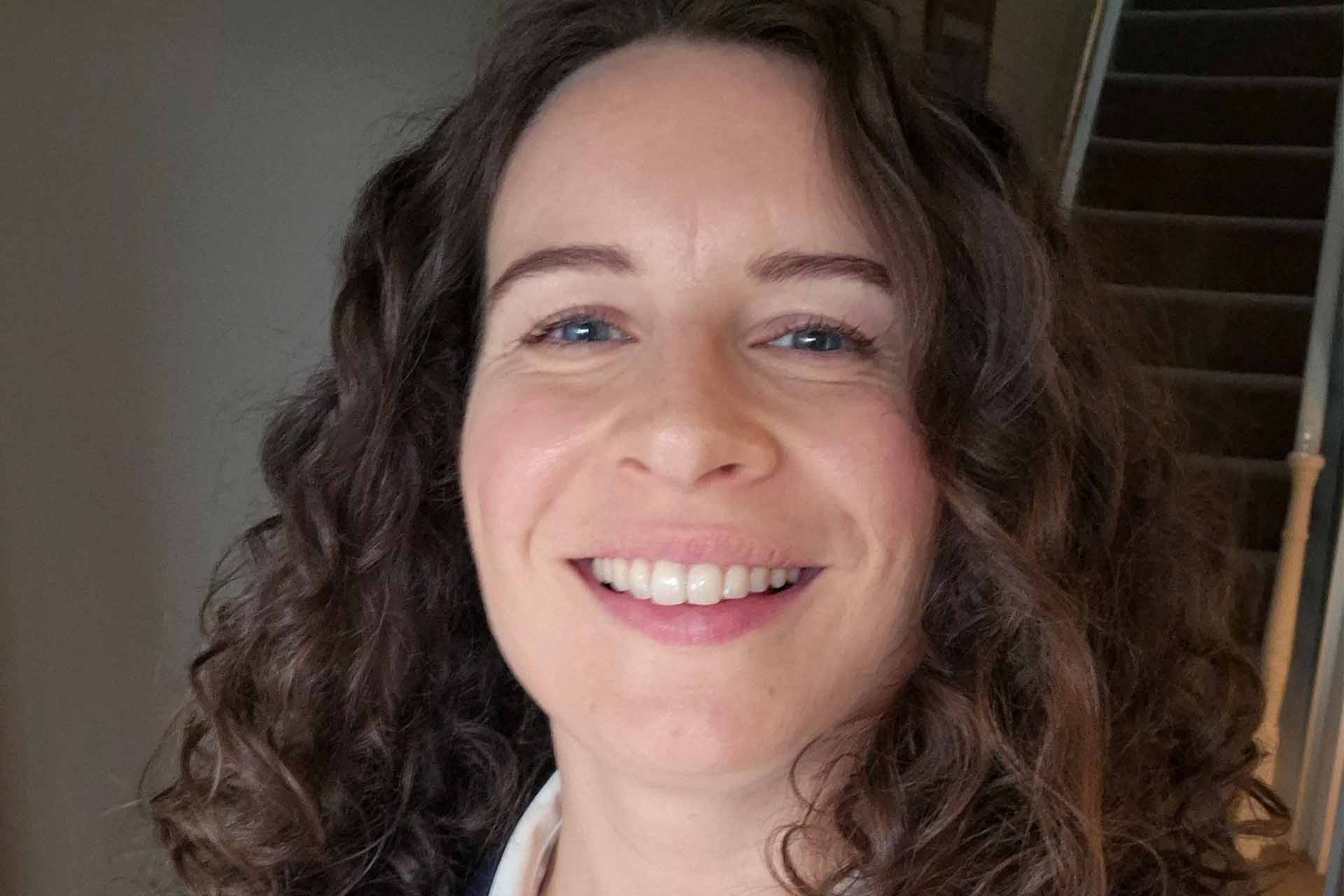 close up of a woman with brown curly hair smiling