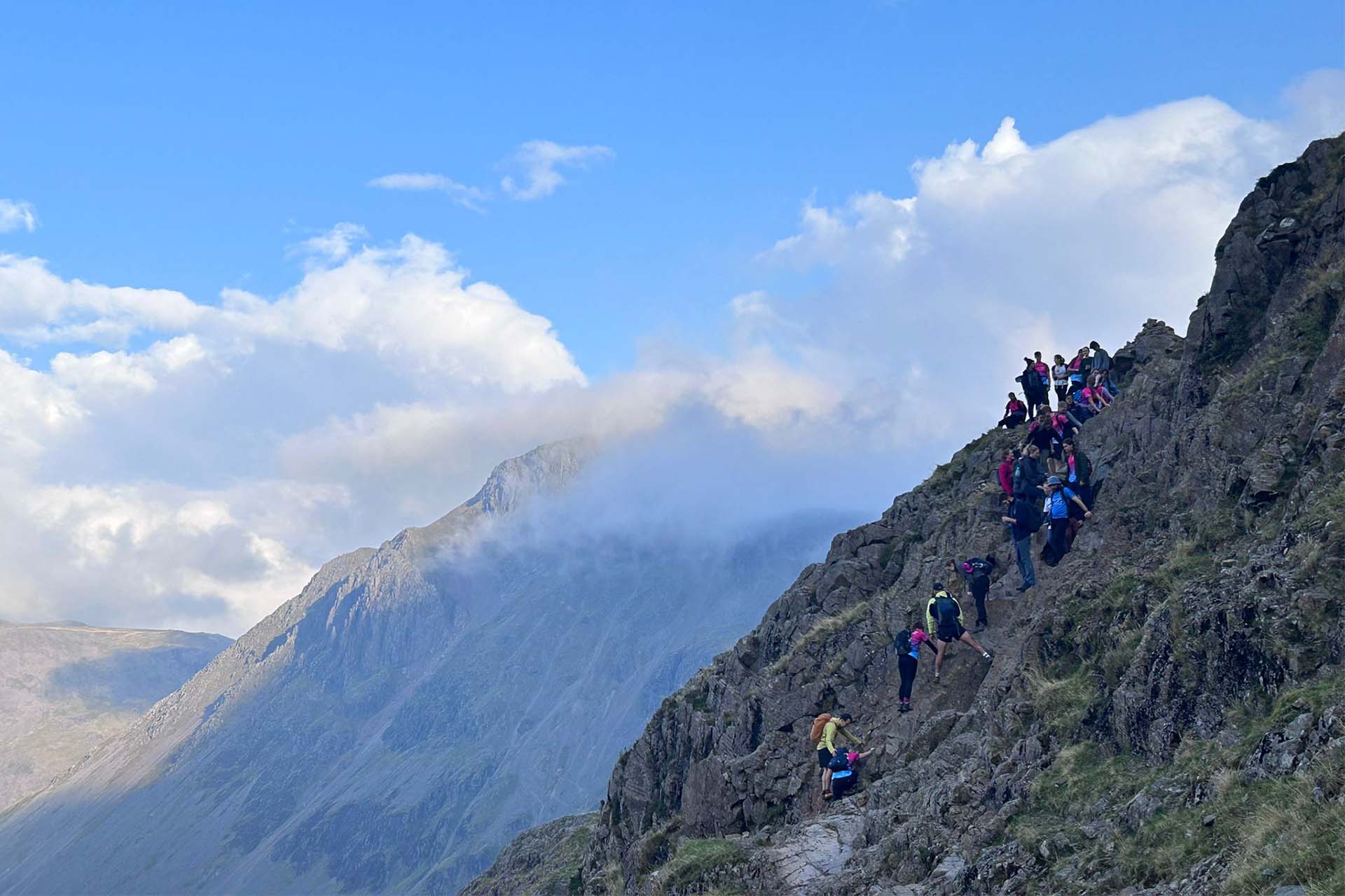 group of people climbing a mountain on a sunny day