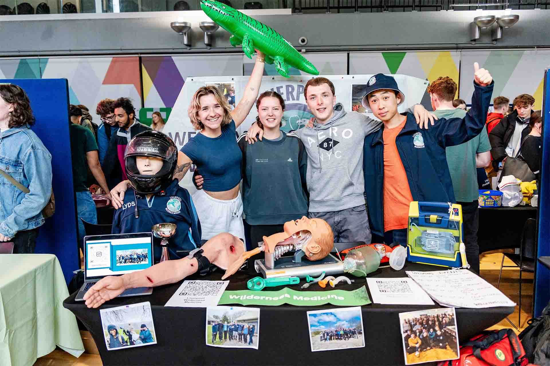 students pose with emergency medicine equipment and an inflatable crocodile