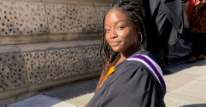 woman poses in graduation gown