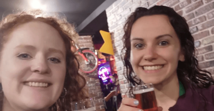 two women raise a glass after completing marathon